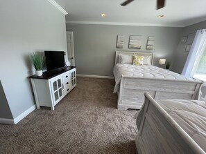 A bedroom with a bed, a TV on a cabinet, and a window.
