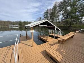 A wooden dock with a covered seating area and a caution sign.