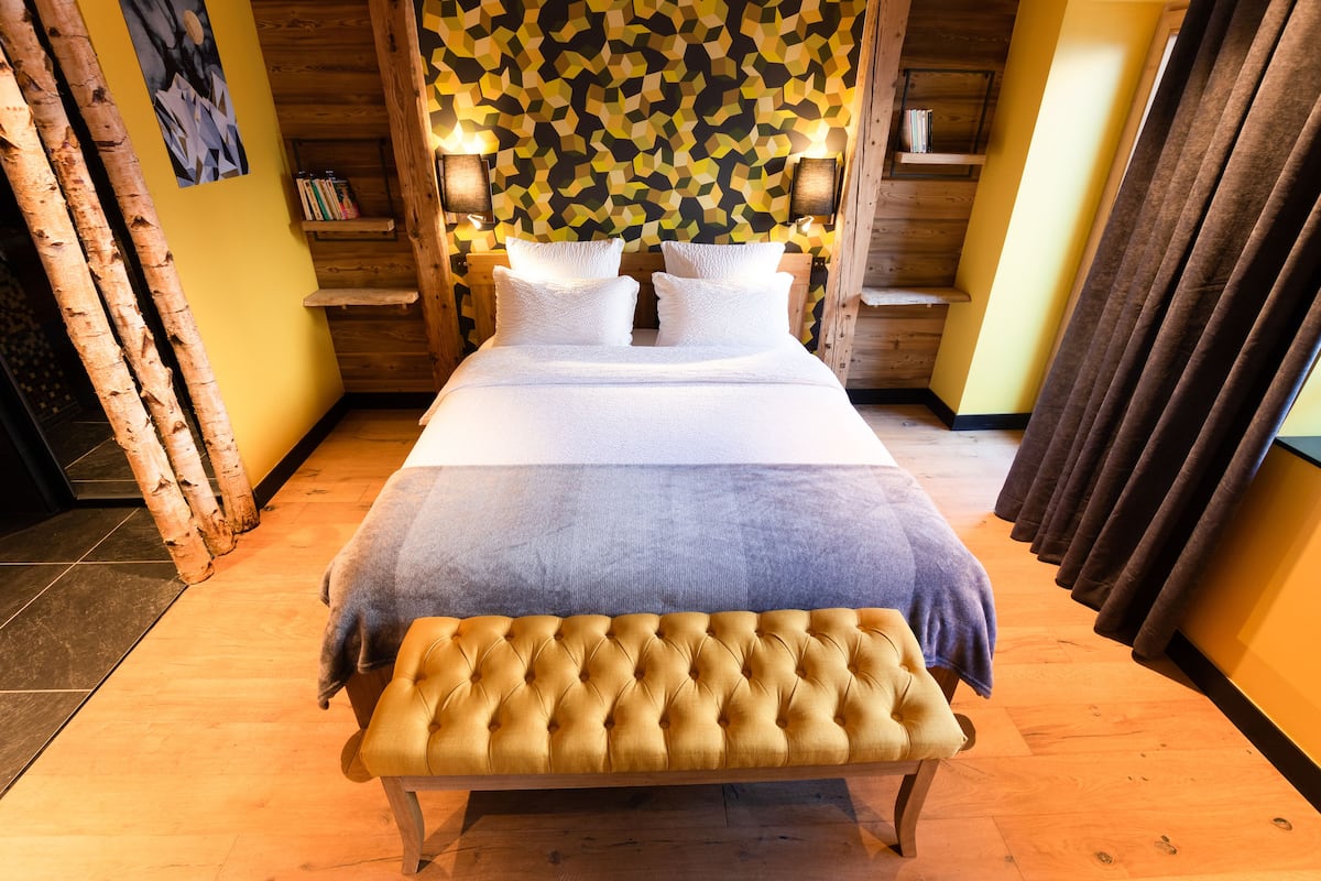 A neatly arranged bedroom with a large bed, bedside tables, and a bench.