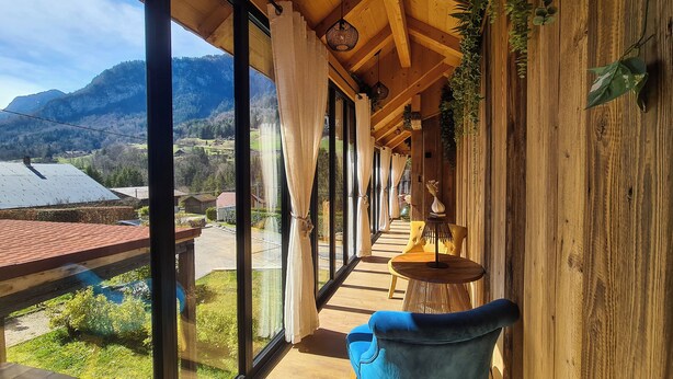 Un pasillo con ventanas amplias, paredes de madera y vistas a un paisaje montañoso.