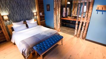 Un dormitorio con una cama grande, un banco, suelo de madera, un armario y un espejo.