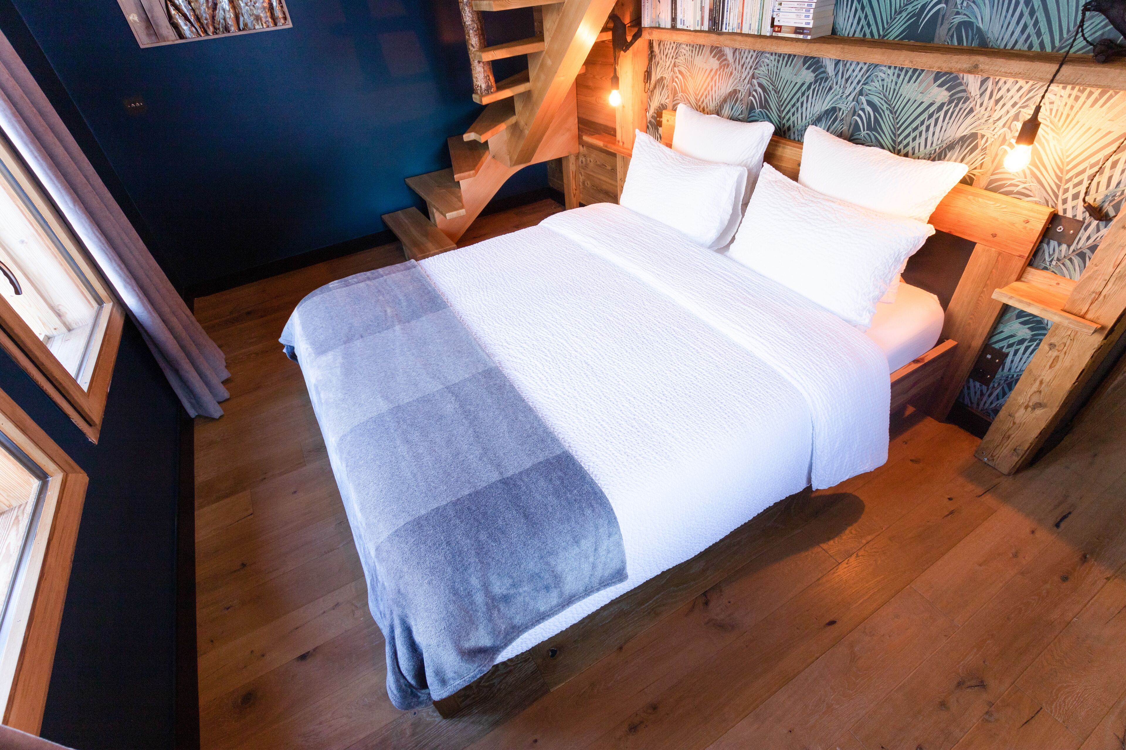 Ein Schlafzimmer mit einem hölzernen Bett, einem Blattmuster-Kopfende und einer Treppe zu einer oberen Ebene.