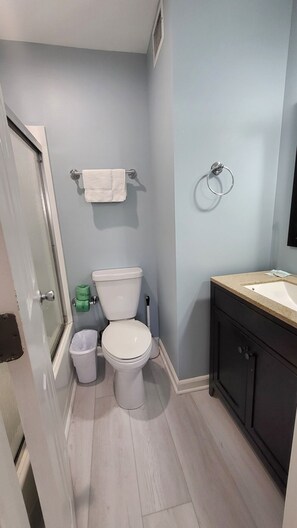 Une salle de bain avec des toilettes, un lavabo et une poubelle.