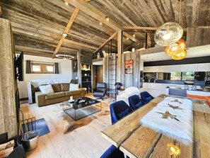 Um interior rústico com teto de madeira, sofá, mesa de jantar e área de cozinha.