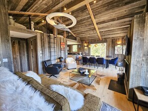 A rustic interior with a sofa, a dining area, and a kitchen.