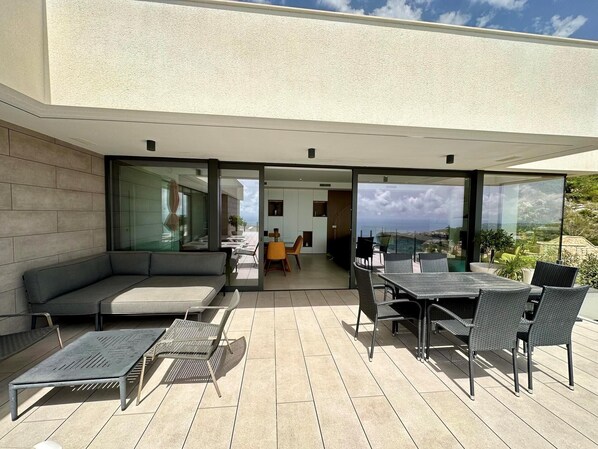 A modern outdoor patio with a sofa, chairs, and a dining table.