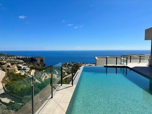 A pool with a clear view of the ocean and a distant town.