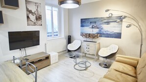A modern living room with a flat-screen TV, a wooden coffee table, a beige sofa, and a unique floor lamp.