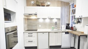 A modern kitchen with white cabinets, a built-in oven, a dishwasher, and a coffee maker.