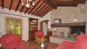 Ein gemütliches Wohnzimmer mit roten Sofas, einem Kamin, einem Bücherregal und einer Steinwand.