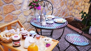 An outdoor breakfast setup with a stone wall backdrop, a table with a tray of food, and a decorative vase with flowers. - Organic breakfast in the garden, Vesuvius view (Castellammare di Stabia)