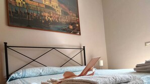 A neatly made bed with a patterned bedspread, a folded towel, and a painting of a cityscape above it. - Organic breakfast in the garden, Vesuvius view (Castellammare di Stabia)