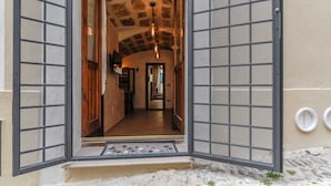 Ein Hotel mit Eingang, einem steinernen Bogen, einem gefliesten Boden und einem zur Innenseite führenden Gang.
