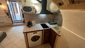 Eine kleine Küche mit Waschmaschine, Mikrowelle und Wasserkocher.
