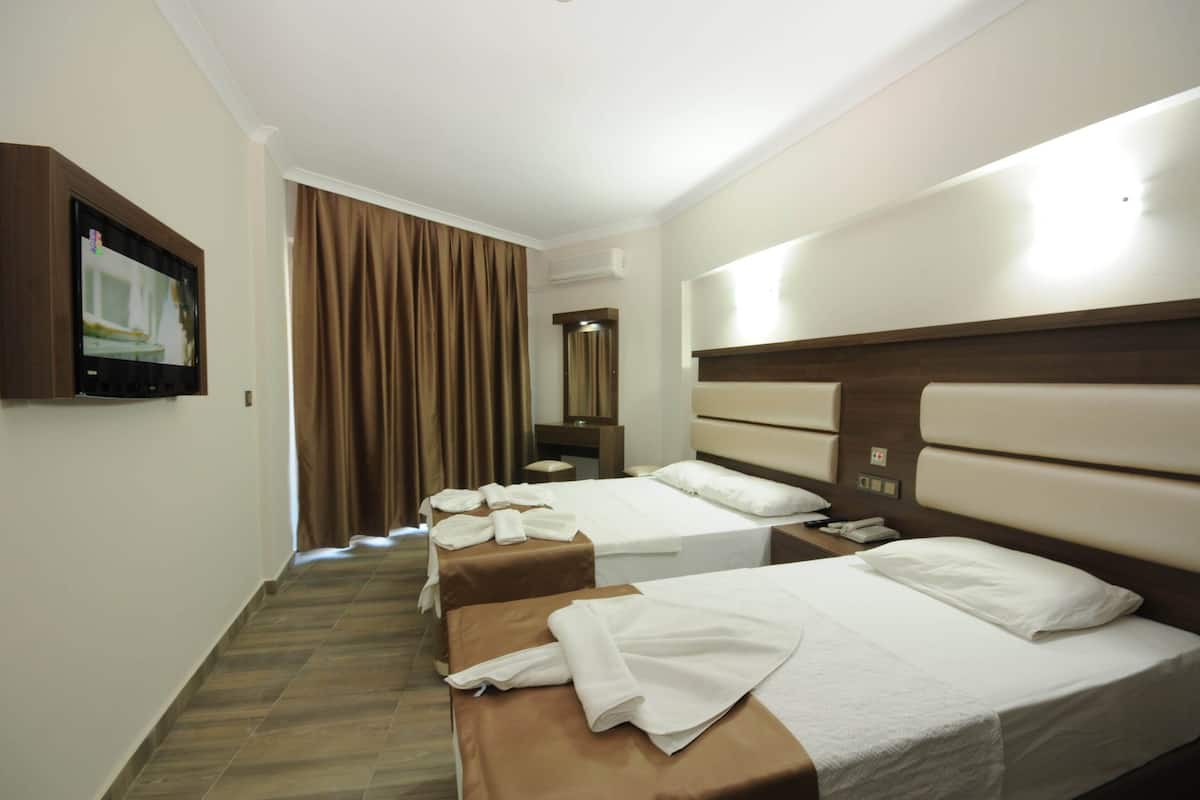 A hotel room with two beds, a TV mounted on the wall, a mirror, and a window with curtains.
