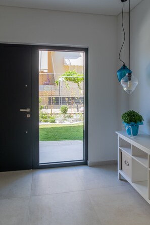 Ein Zimmer mit einer Schiebetür zum Garten, einem weißen Konsolentisch mit einer Topfpflanze und einer Pendelleuchte.