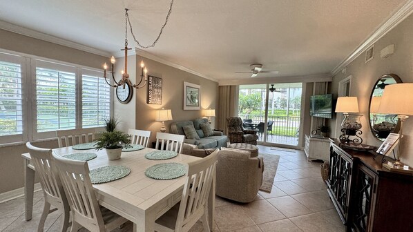 A spacious living area with a dining table, chairs, a sofa, and a television.