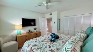 Una camera da letto con un letto, una TV, una ventola a soffitto, una cassettiera e un armadio.