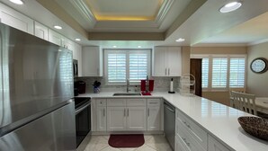 A modern kitchen with stainless steel appliances, white cabinetry, and a large island. - Essex 106N: 5 Min walk to Beach, Movies, Restaurants (Marco Island)
