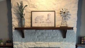 Una chimenea de piedra con repisa, un boceto enmarcado y una decoración con molino.