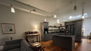 A modern kitchen with a central island, wooden flooring, and pendant lighting. - Palafox Loft 122, sleeps 2 (Pensacola)