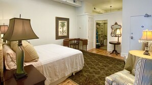 A bedroom with a skylight, a bed, a desk, a chair, and a small table with a lamp. - Palafox Loft 122, sleeps 2 (Pensacola)