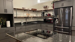 A modern kitchen with grey cabinets, a stainless steel refrigerator, a microwave, and a built-in stove. - Palafox Loft 122, sleeps 2 (Pensacola)