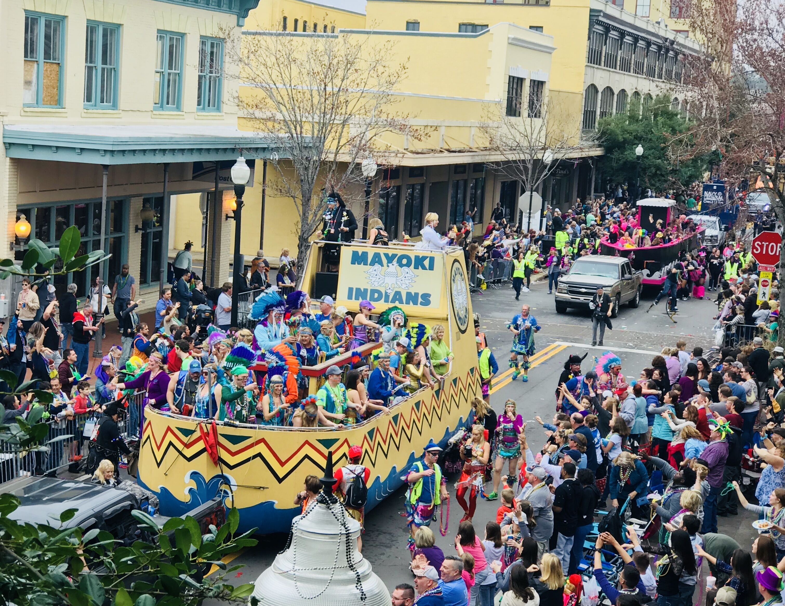 A parade float with "MAYOKI INDIANS" text, surrounded by a crowd.