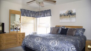 Ein Schlafzimmer mit einem großen Bett, einer hölzernen Kommode und einem Deckenventilator.