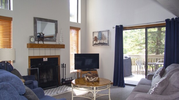 Ein Wohnzimmer mit Kamin, Fernseher und Blick ins Freie.