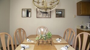 Ein Esszimmer mit Holztisch, vier Stühlen, einer Kandelaber und einer Zimmerpflanze als Tischdeko.