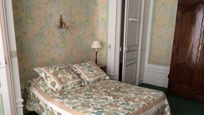 Une chambre à coucher avec un lit, un papier peint à motifs floraux et une armoire en bois.