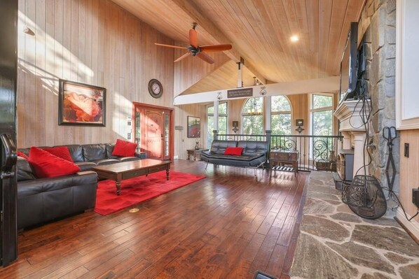 A spacious living room with a wooden ceiling, a fireplace, and a stone accent wall. - Luxurious Escape-DOUBLE Masters and GOURMET Kitchen with New air conditioning (Shaver Lake)