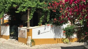 Un edificio storico con una strada acciottolata, una facciata bianca e gialla e un cartello che indica che si tratta di una casa di campagna.