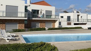 Una moderna casa a due piani con piscina, patio coperto e balcone con mobili da esterno.