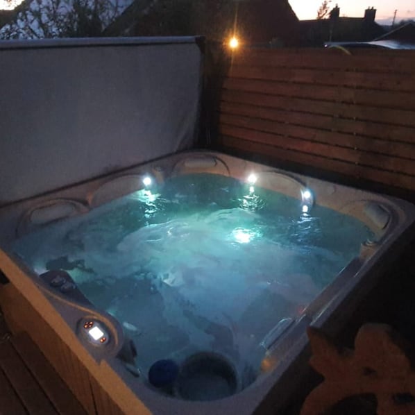 A hot tub with a wooden deck and a brick wall in the background. - Casita Lodge | Hot tub Stay for two in the Forest of Dean (Cinderford)