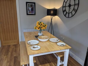 A dining table with plates, a bowl, and a vase of sunflowers.