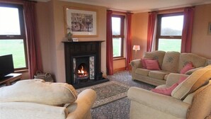 A cozy living room with a fireplace, two sofas, and a television. - Allanhead Cottage -  a cottage that sleeps 8 guests  in 3 bedrooms (Kirkcudbright)