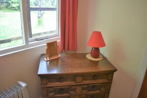 Ein Holzkommode mit einer Lampe und einem Bilderrahmen darauf.