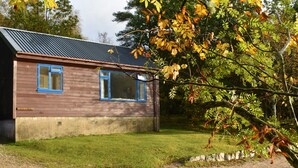 A wooden house with two blue-framed windows, a metal roof, and a grassy yard. - Camus Slatach - sleeps 4 guests  in 2 bedrooms (Glenfinnan)
