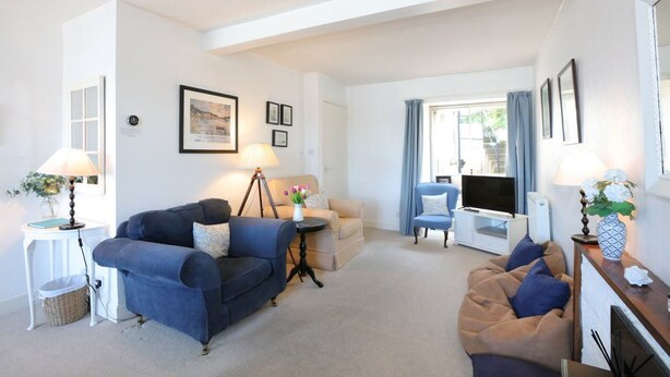 A living room with a blue sofa, a beige sofa, a small table with a lamp, and a TV stand.