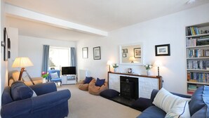 A living room with a fireplace, sofas, a television, and a bookshelf.