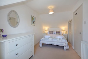 A bedroom with a bed, a dresser, a mirror, and a picture on the wall.