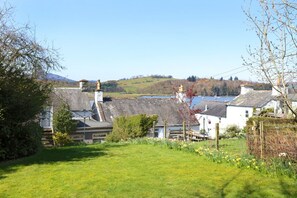 A rural landscape with houses, a field, and a body of water in the distance.