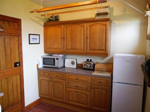 Une cuisine avec des meubles de rangement en bois, un four à micro-ondes, un grille-pain et un réfrigérateur.