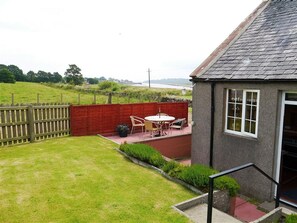 Une maison avec une clôture rouge, une terrasse avec une table et des chaises, et une vue sur une rivière.