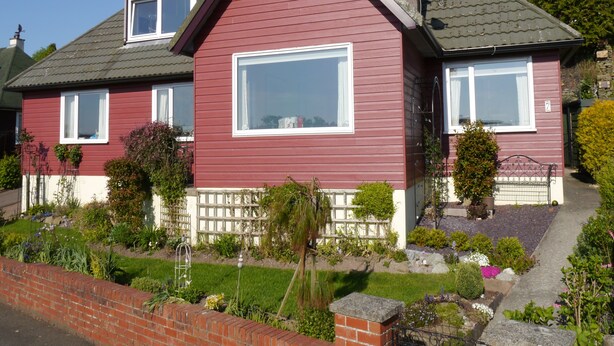 A two-story house with a red exterior, large windows, and a well-maintained garden. - Arakhova -  a house that sleeps 10 guests  in 4 bedrooms (Kirkcudbright)