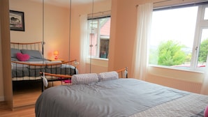 A bedroom with a large bed, a smaller bed, a window with a view, and a bedside table with a lamp. - Arakhova -  a house that sleeps 10 guests  in 4 bedrooms (Kirkcudbright)