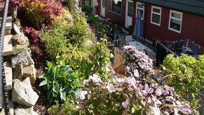 A residential area with a red house, a stone wall, and various plants. - Arakhova -  a house that sleeps 10 guests  in 4 bedrooms (Kirkcudbright)