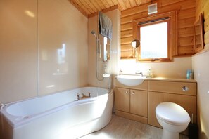 A bathroom with a bathtub, a sink, and a toilet. - Birchlea -  a lodge that sleeps 6 guests  in 3 bedrooms (Kippford, Dalbeattie)